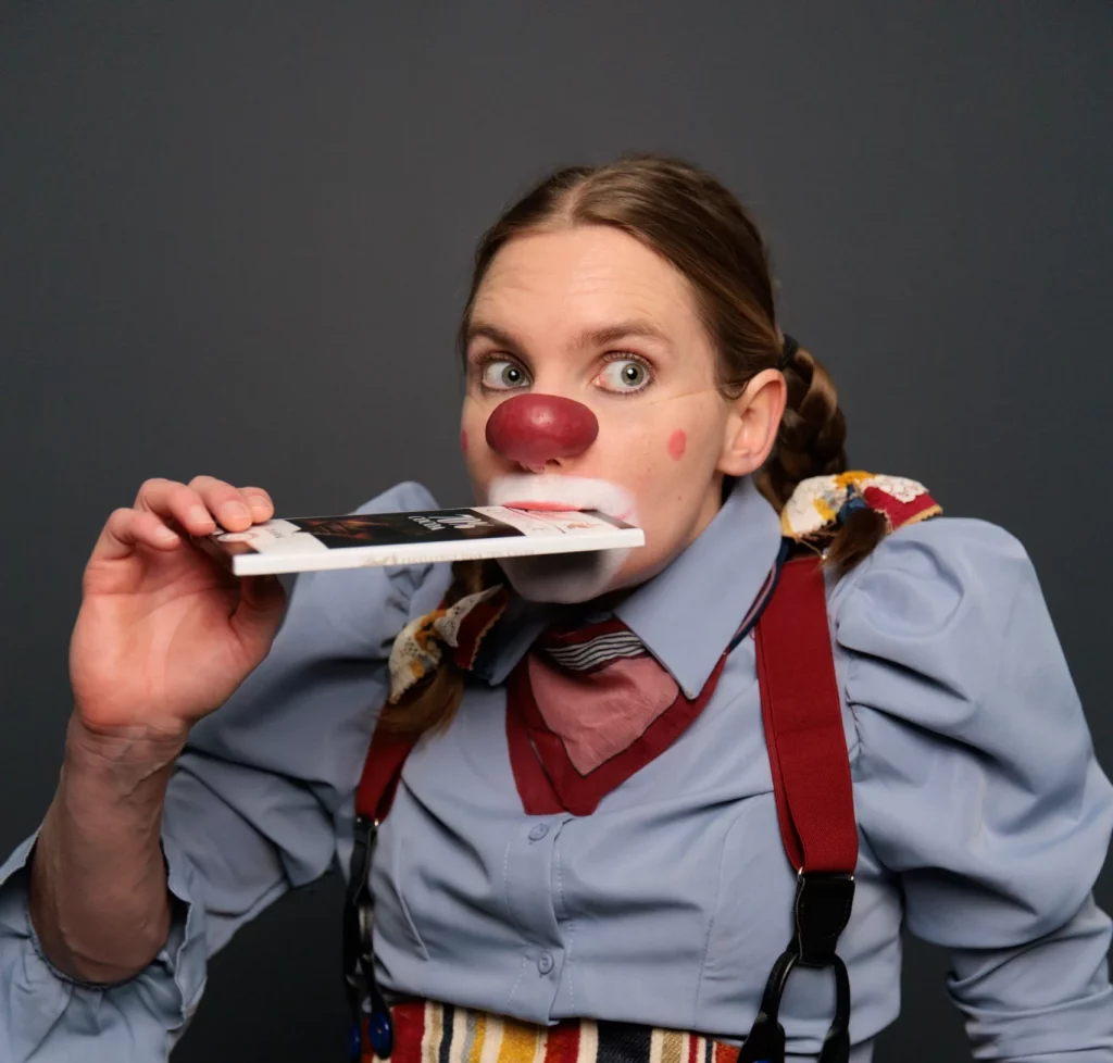 Pamela Pilawa in Clown Costume posing with a chocolate bar showcasing her family friendly theatre shows in Sydney